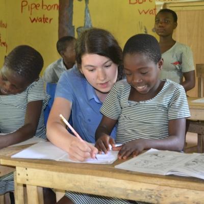 Teaching volunteer helps her student with classwork during her teaching work experience in Ghana A teacher helps a child at one of our Projects Abroad volunteer teaching placements in Ghana